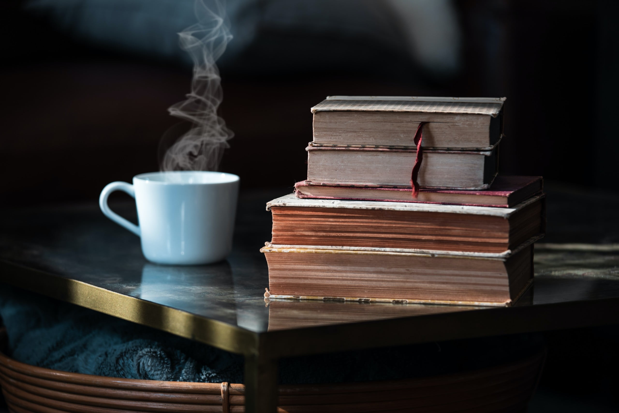 A steaming cup of coffee next to a stack of old books