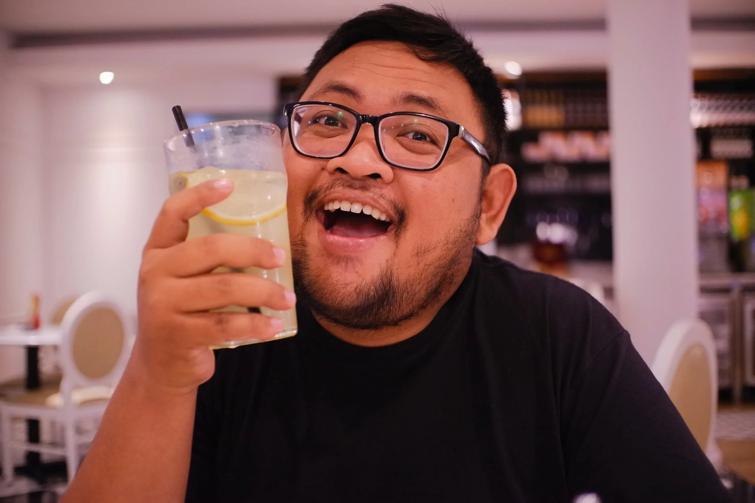 man in black crew neck shirt holding clear drinking glass