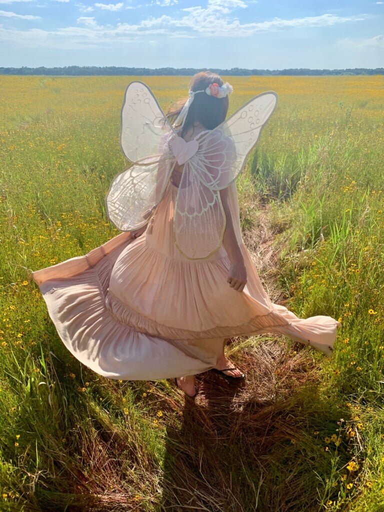 woman in fairy costume standing on green field
