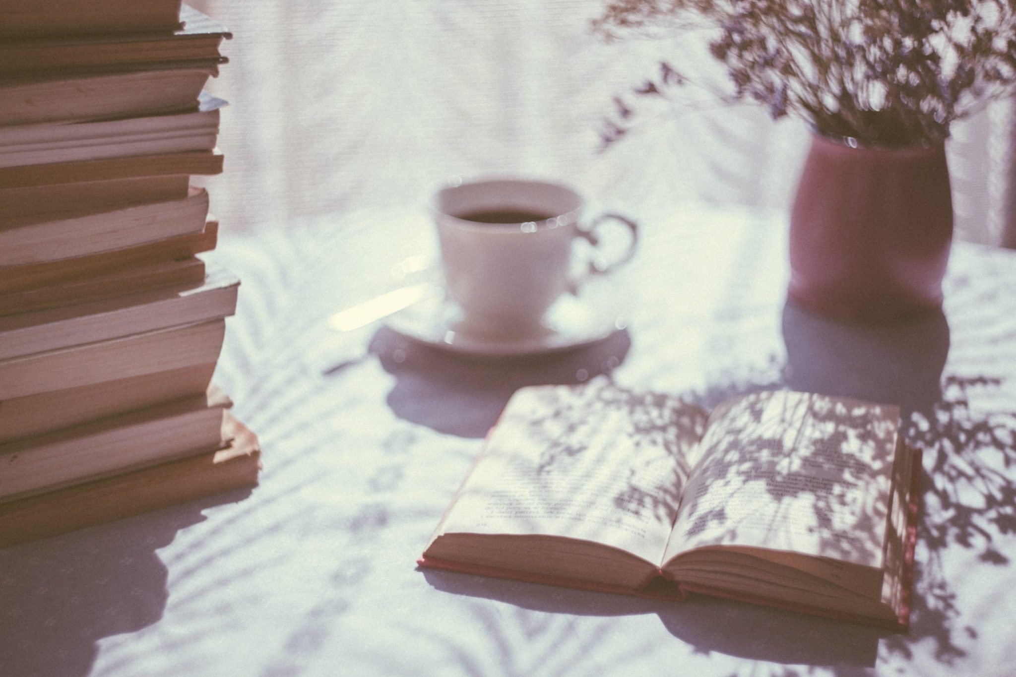 Open book beside white ceramic teacup on saucer stockpack unsplash scaled[1]